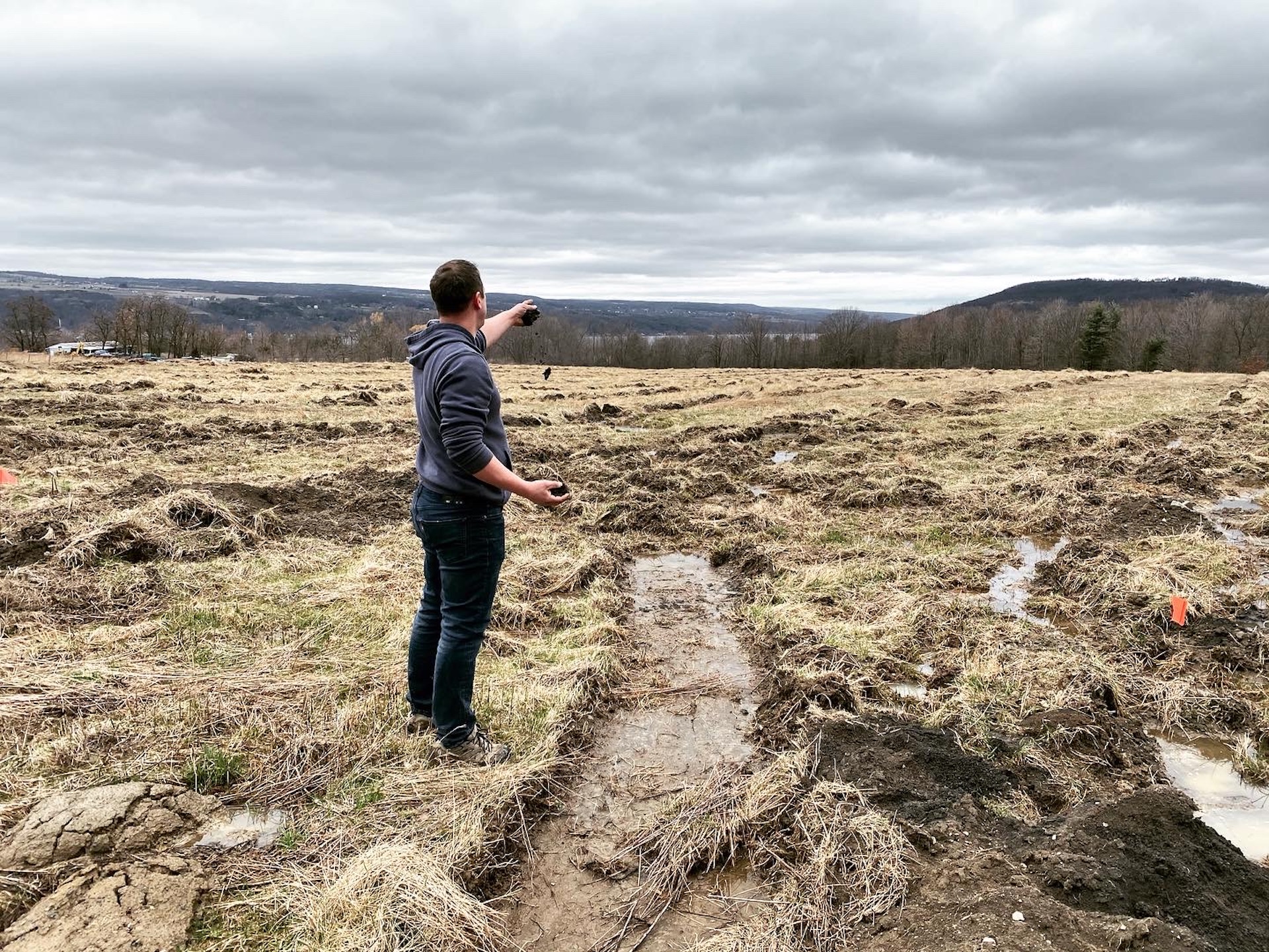 Peter Weis standing in the middle of a field that will become our first vineyard site.  The property overlooks Keuka Lake and Peter is turned away with his arm extended out toward the lake in the background. 